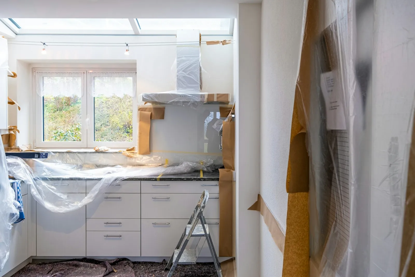 Kitchen mid-renovation with units covered in protective sheeting