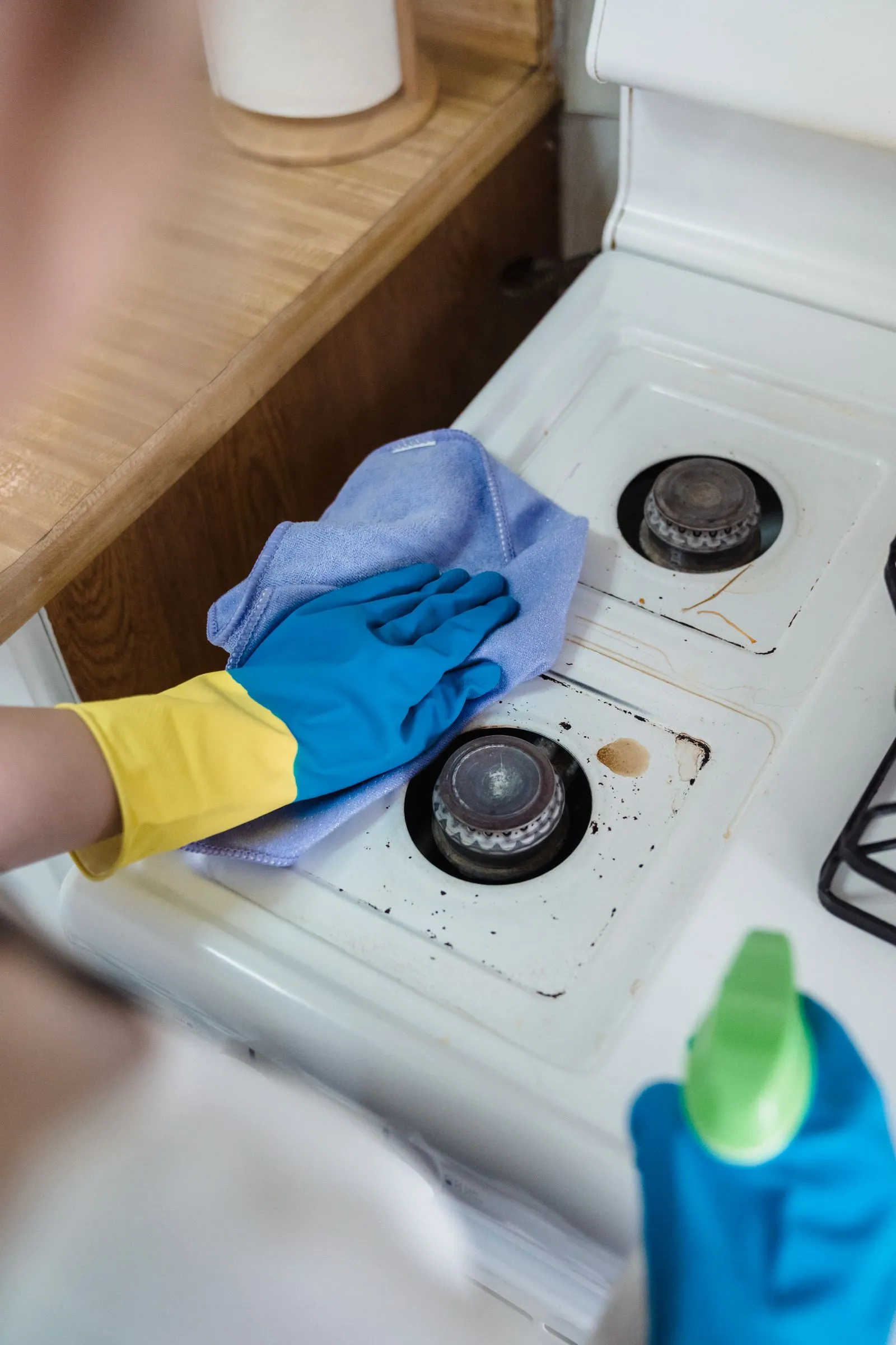Gloved hands cleaning a gas hob