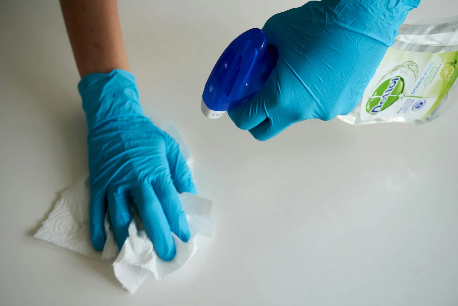 Gloved hands wiping a white surface