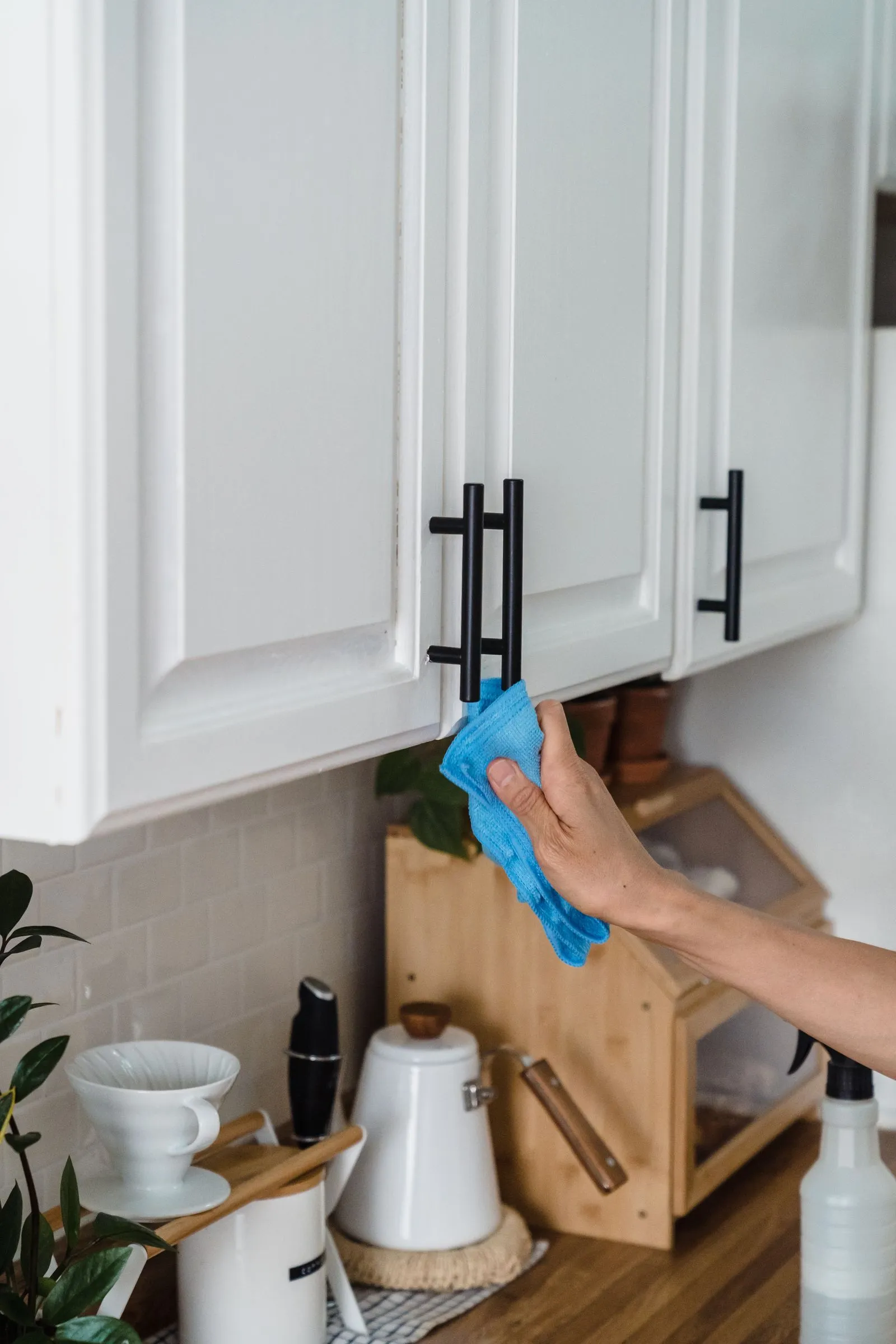 Wiping kitchen cupboard handles with a cloth